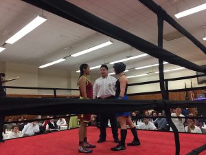Two boxers size each other up while listening to the referee’s instructions.